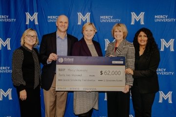 Oxford International Education Group and ϲʿ officials pose in front of large cardboard check symbolic of the $62, 000 donation they made to the university